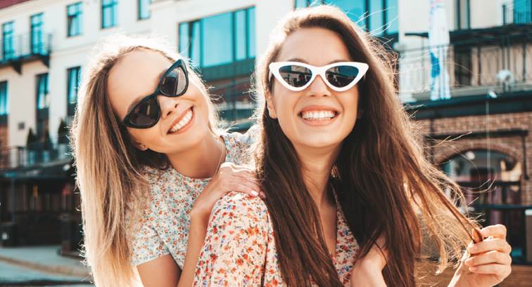 Two young girls wearing sunglasses and smiling